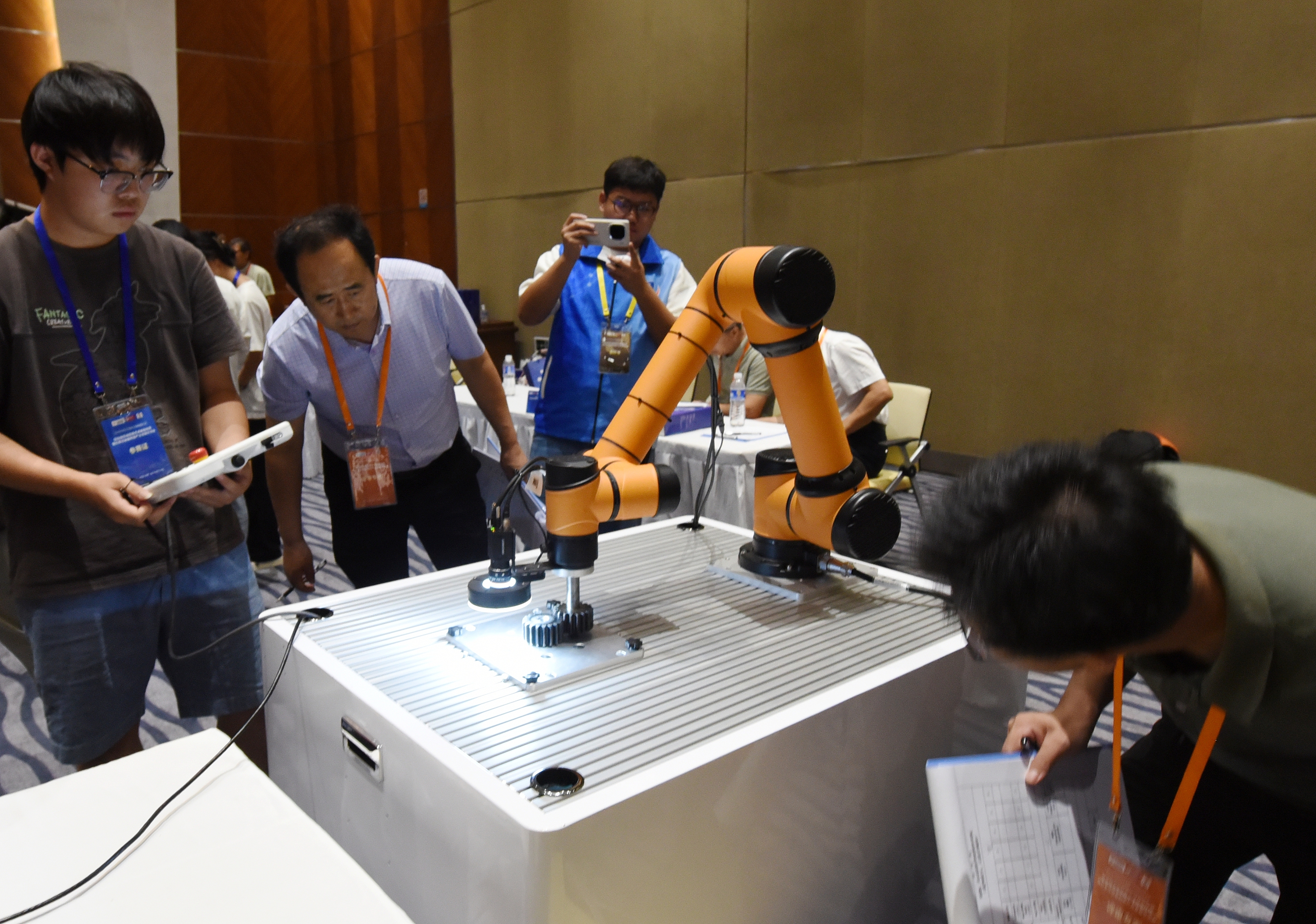 联播+|三个“桩”撑起“一盘棋” 2025年中国大学生机械工程创新创意大赛智能精密装配赛京津冀鲁联赛现场,评委对参赛选手进行实操调试评比。